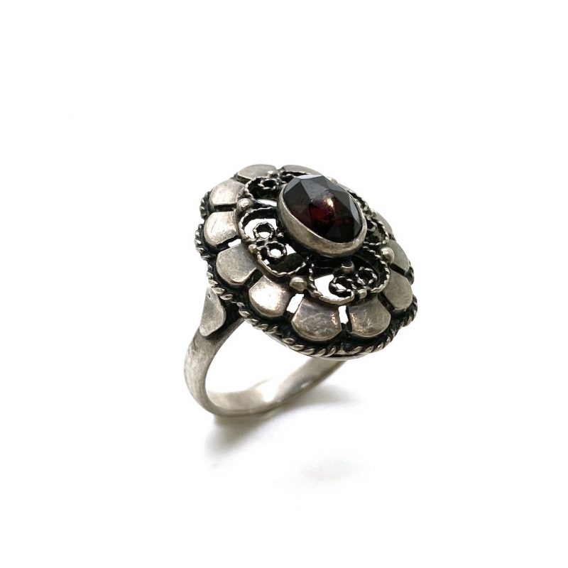 Zilveren ring in bloemendesign met in het midden een wijnrode granaat edelesteen.